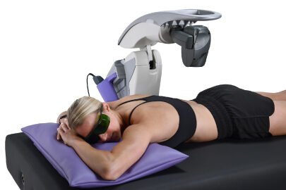 Patient resting comfortably face down beneath an MLS robotic laser while wearing protective eyewear
