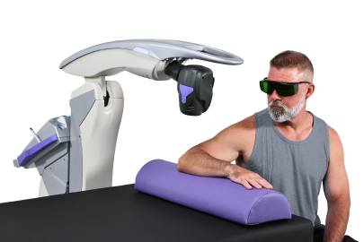 MLS robotic laser positioned above a seated patient's arm while he wears protective eyewear