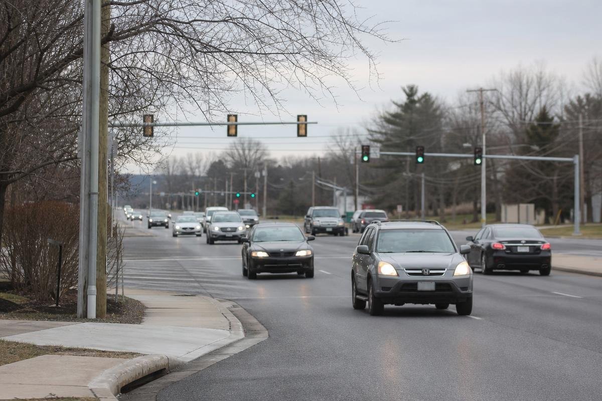 Cars driving on a multi-lane road at an intersection with traffic lights near Alexandria