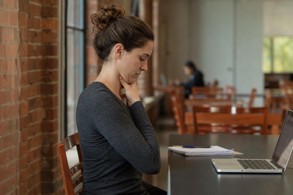Woman at a table performing a chin tuck stretch to relieve neck strain