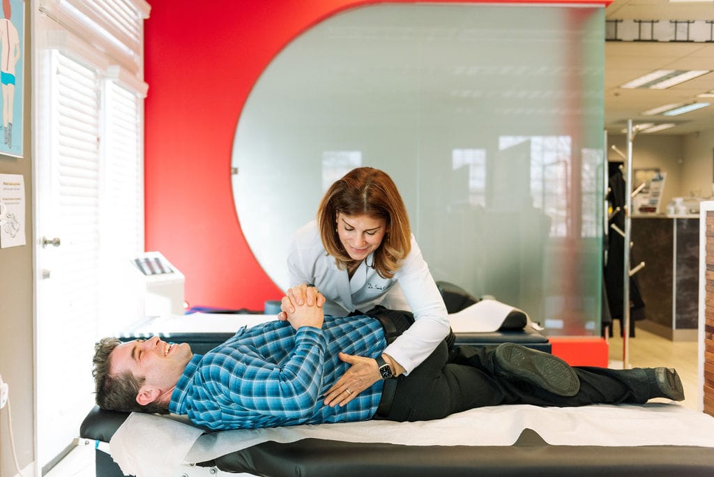 Chiropractor guiding a patient through supervised rehabilitative exercise